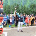 John Morris, a member of the Yanyeidí clan who once called the site home, raises his arm in triumph after helping to install the Gooch (wolf) totem pole. June 6, 2018. (Photo by Adelyn Baxter/KTOO)
