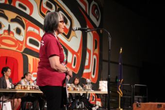Rosita Worl on stage at Centennial Hall during the food competition. (Photo by Elizabeth Jenkins/Alaska's Energy Desk)