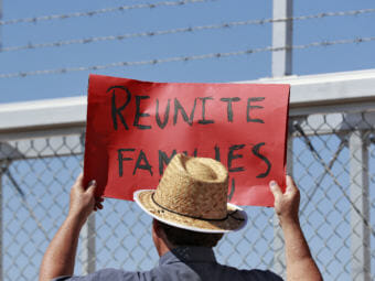 A protester holds a sign outside a closed gate at the Port of Entry facility, last week in Fabens, Texas, where tent shelters are being used to house separated family members. (Photo by Matt York/Associated Press)