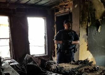 A Juneau Police Department officer stands in the burned third-floor bedroom where the fire that damaged the Dapcevich House began. (Photo courtesy of Ernestine Hayes)