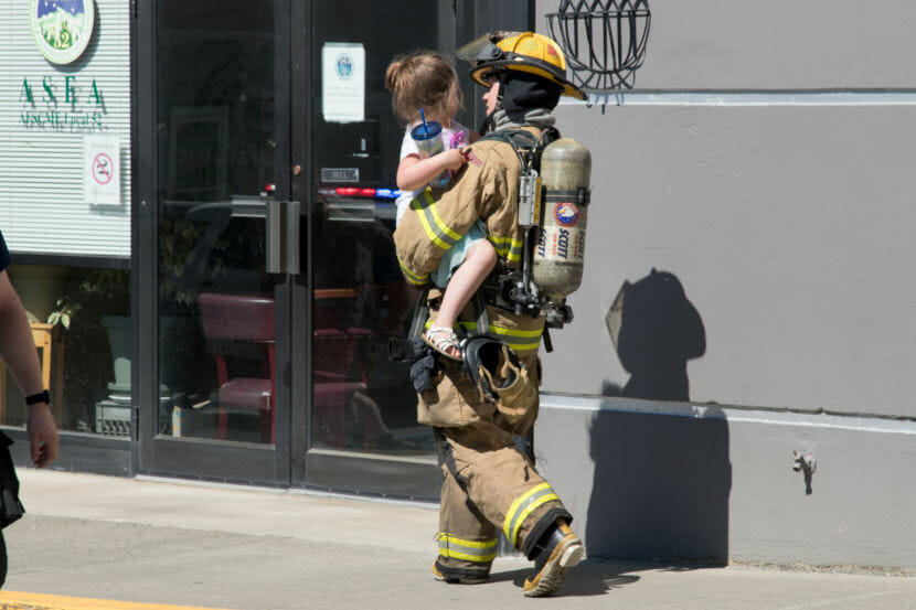 A firefighter carries a child evacuated from an upper floor of the Mendenhall Towers on Thursday July 5th, 2018 (Photo by Mikko Wilson/KTOO)