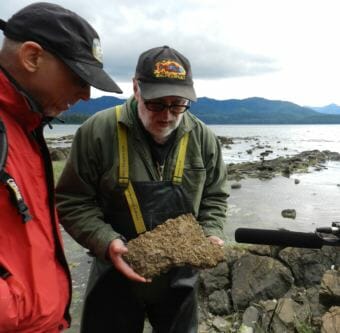 Dave Strassman, left, and Ray Troll investigate a block of limestone crusted with fossil shells. (Photo courtesy Josef Quitsland)