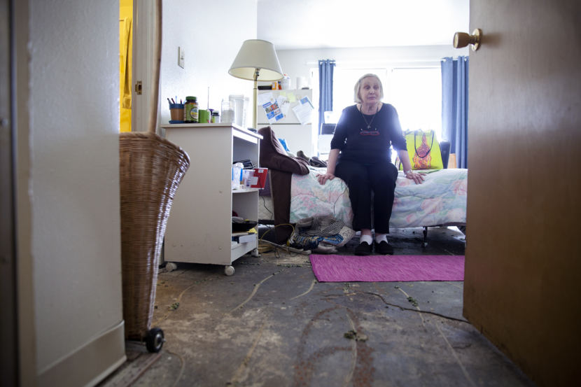 Terry Baker sits on her bed in an apartment recently stripped of wet carpet on July 12, 2018, at the Mendenhall Tower Apartments in Juneau. Baker's apartment is near one that caught fire and damaged the building extensively. (Photo by Rashah McChesney/Alaska's Energy Desk)
