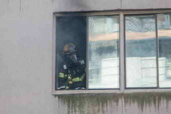A firefighter responds to a fire in apartment 301 of the Mendenhall Towers on Thursday July 5th, 2018 (Photo by Mikko Wilson/KTOO)
