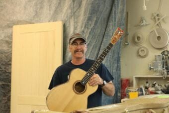 Greg Gerard holds his latest guitar at his shop in Homer. (Photo by Aaron Bolton/KBBI)