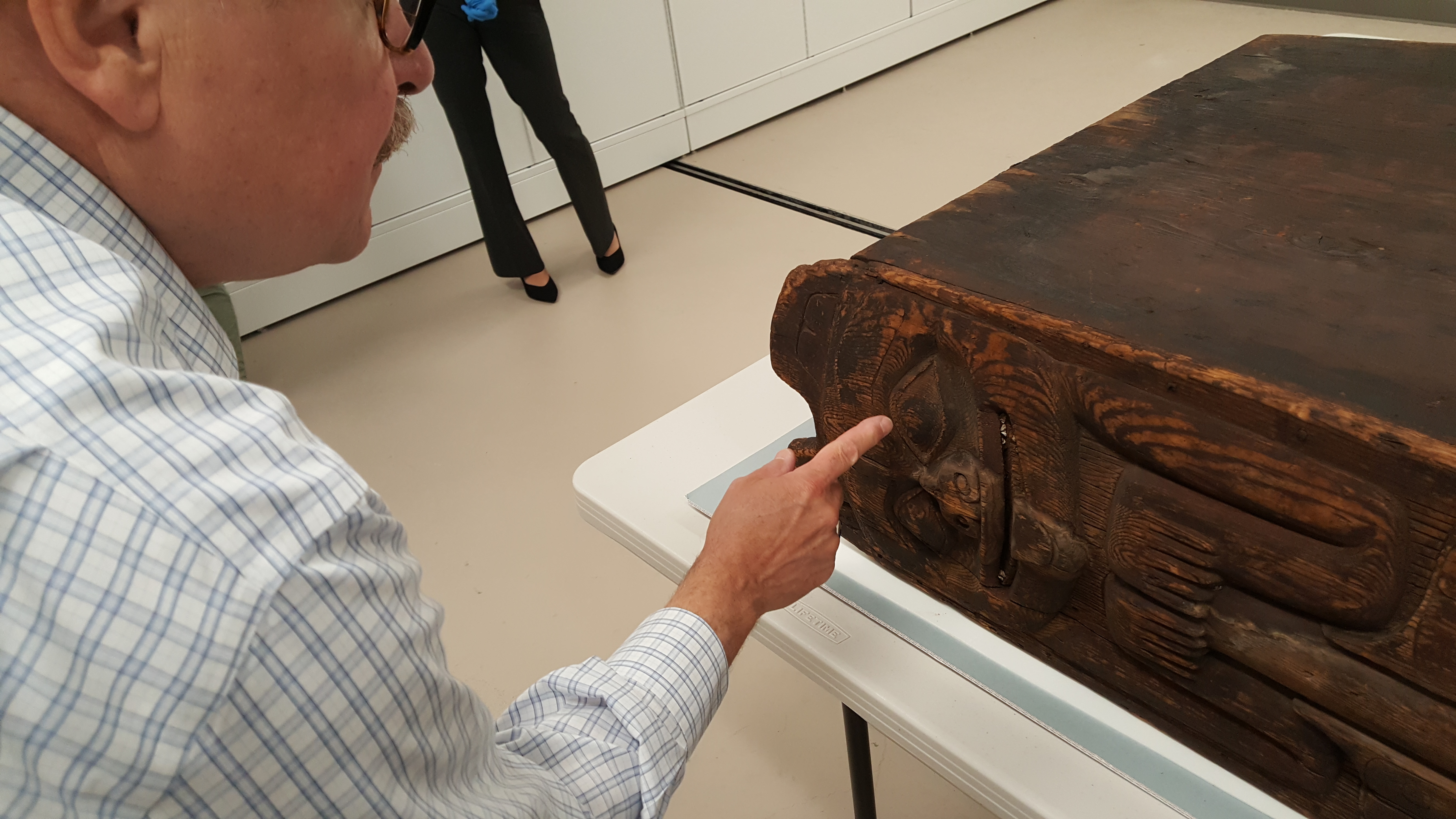 Chuck Smythe points out detail of a bear carving on a bentwood box drum that were painted long ago. (Photo by Tripp J Crouse/KTOO)