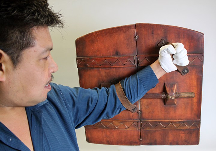 Artist, Andrew Abyo, holds his war shield which is in the permanent collection of the Alutiiq Museum and Archaeological Repository join Kodiak. (Photo courtesy the Alutiiq Museum)