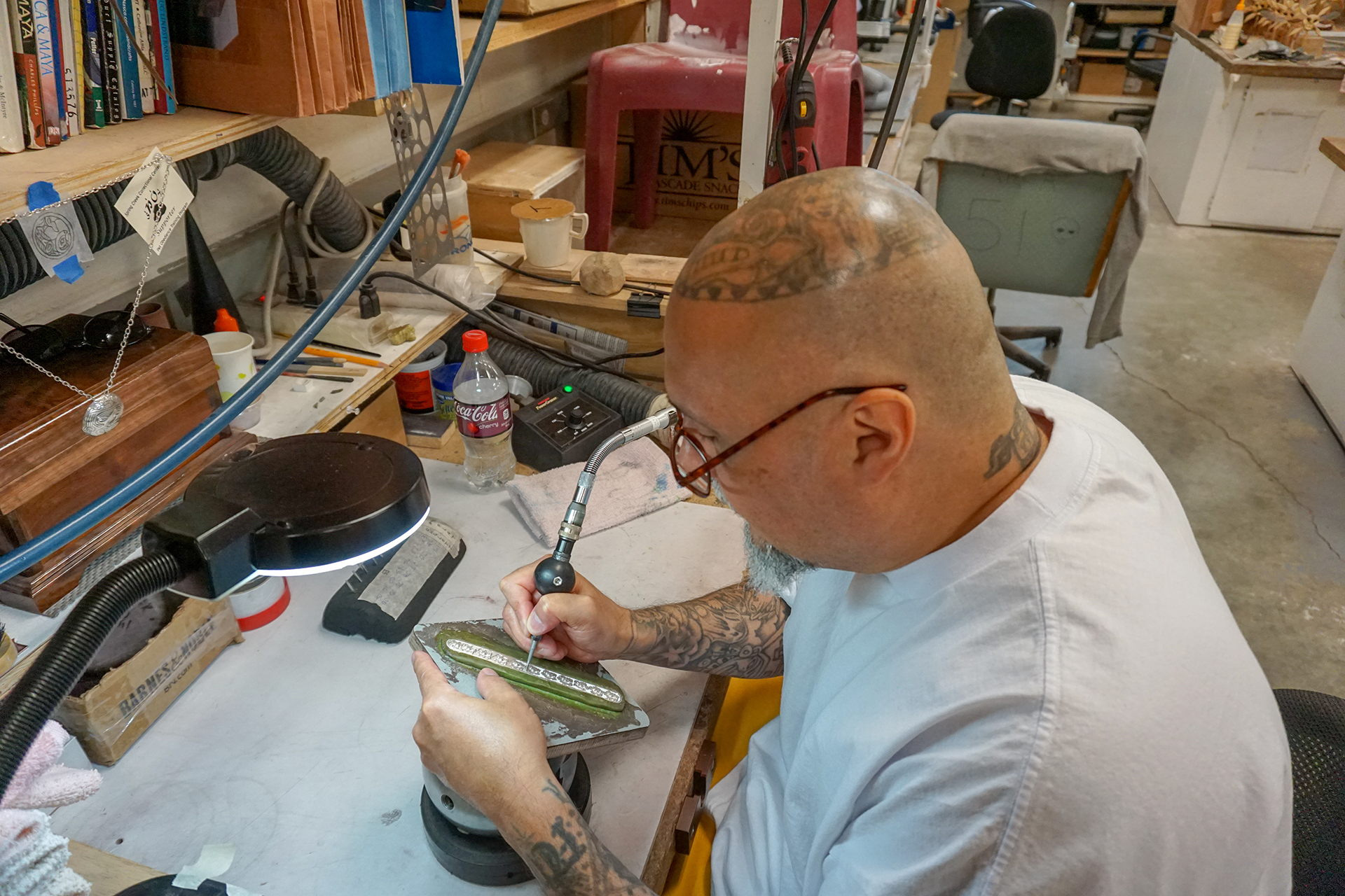 Anthony Garcia engraves a silver bracelet in the hobby shop at Spring Creek Correctional Center. (Photo by Anne Hillman/Alaska Public Media)