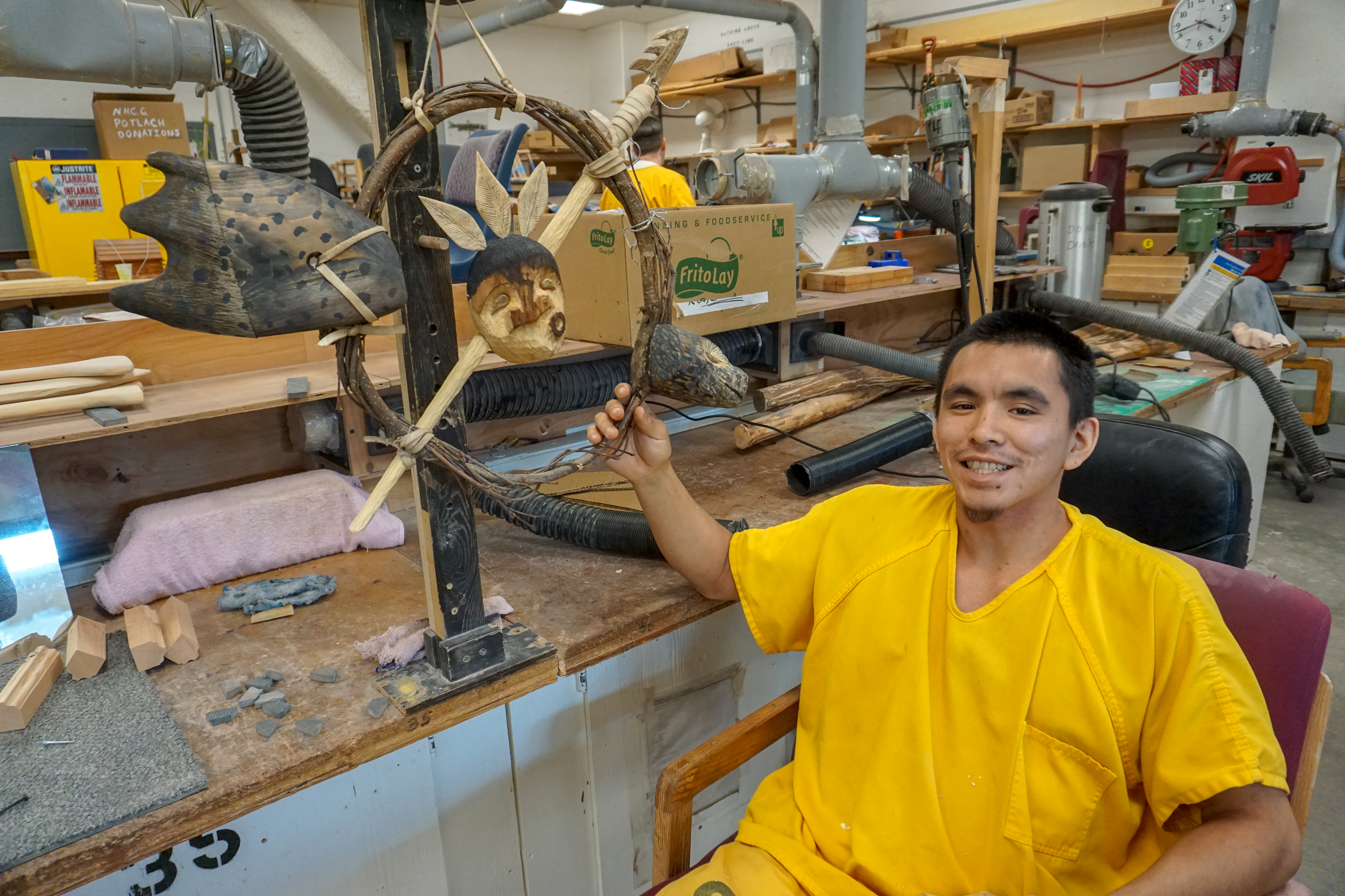 Nathanial Kangas shows off his first carving, a mask and a seal in the hobby shop at Spring Creek Correctional Center. (Photo by Anne Hillman/Alaska Public Media)