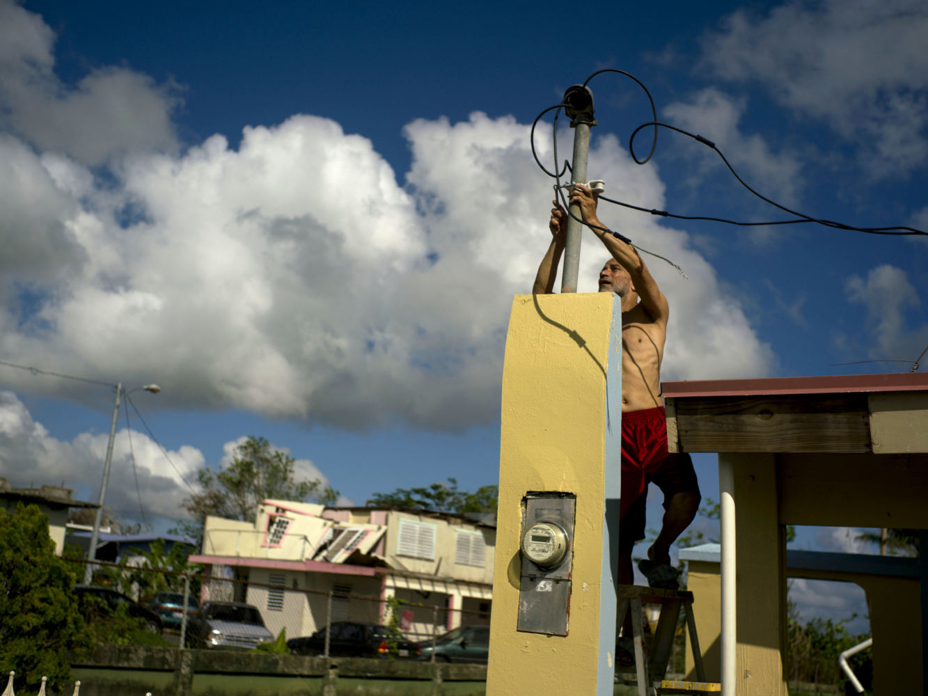 In October 2017, a resident tries to connect electrical lines downed by Hurricane Maria in Toa Baja. Puerto Rican officials say electricity has returned to all residents without it after the hurricane. (Photo by Ramon Espinosa/Associated Press)