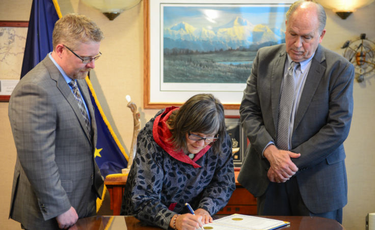 Valerie Nurr'araaluk Davidson signs paperwork as part of a swearing in ceremony with Gov. Bill Walker, right, and Chief of Staff Scott Kendall in Anchorage on Tuesday, Oct. 16, 2018.