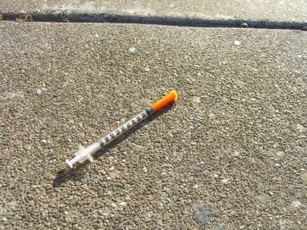 A needle on the sidewalk.