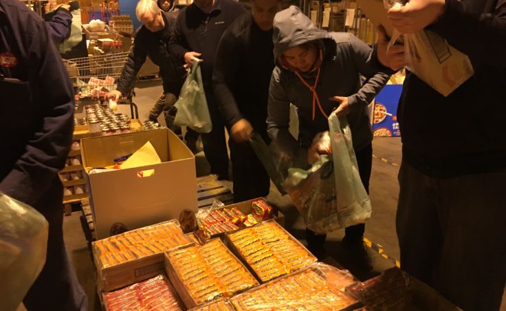 IGA employees on Dec. 19, 2018 fill bags with cereal, ramen noodles, and other goods to send home with Juneau students. (Photo by Zoe Grueskin/KTOO)