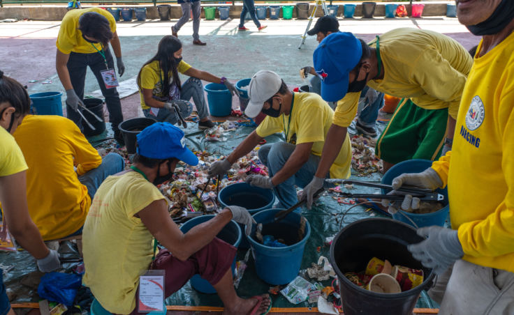 Volunteers sort trash items in a brand audit of plastic waste in Navotas, Manila. They keep track of the brands they find and publish results on the Web. Their goal is to pressure companies to change their plastic packaging.