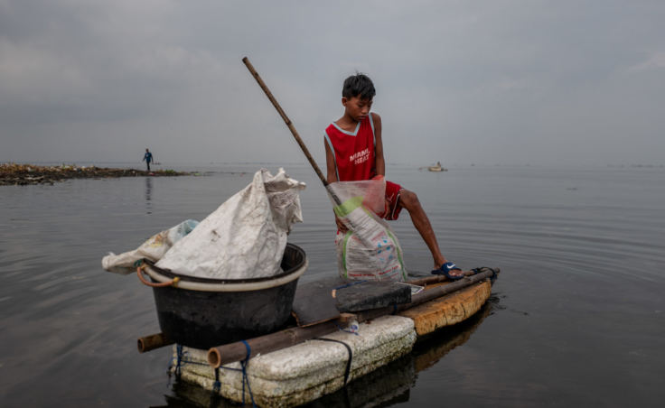 Children fill sacks with plastic trash from Manila Bay that they intend to sell to recyclers. (Photo by Jes Aznar for NPR)