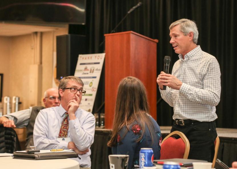 Juneau City Manager Rorie Watt looks on as CLIAA President John Binkley speaks at the Southeast Conference Mid-Session Summit in Juneau on Feb. 13, 2019. (Photo by Heather Holt/Southeast Conference)