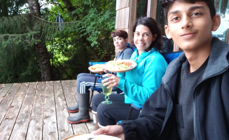 Zain Mufti (right) eating with his host family. Mufti says his family at home in Pakistan are confused by his Alaskan diet, which contains less meat. He says he tells them, "There’s a whole world beyond meat -- there’s cheese!" (Photo used with permission)