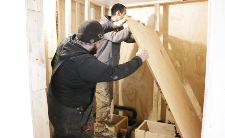 For many Eek homes, installing plumbing means building a bathroom in the house. Plumbers Nicholas Henry and Robert Sitton are pictured here on February 20, 2019. (Photo by Anna Rose MacArthur/KYUK)