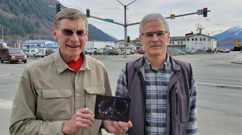 Gene Miller, left, and Craig Wilson pose for a photo in downtown Juneau on March 21, 2019. Miller is a retired forester and member of Juneau Veterans for Peace and Juneau Urban Forestry Partnership. Wilson is president of Juneau Veterans for Peace. The groups recently got an OK from a Juneau Assembly committee to landscape the peace sign at the end of Commercial Boulevard. Miller is holding a photo of the peace sign lit by people with headlamps and flashlights taken on Martin Luther King Jr. Day in 2014.