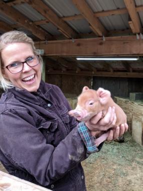 Kelli Foreman shows off a newborn piglet at the Baptist Mission’s Heritage Farms.