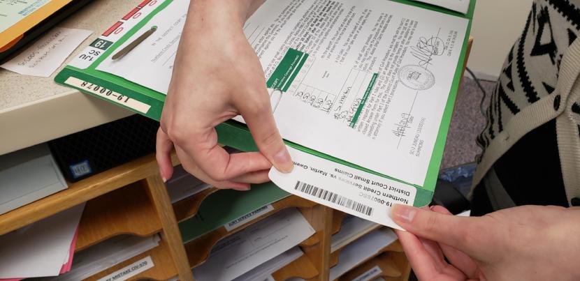 Records clerk Amanda Beebe-Bay puts a bar code label on a new small claims case file in the Dimond Courthouse in Juneau on April 22, 2019. Each time the case file moves, the bar code is supposed to be scanned, like a library book.