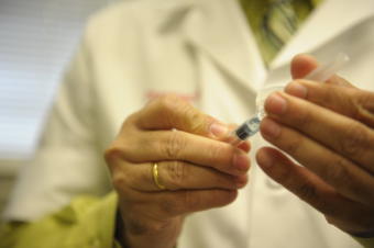 A medical professional prepares a vaccination shot syringe.