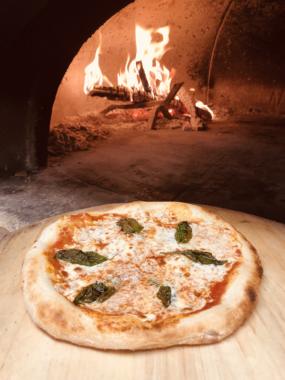 A margherita pizza from Forno Rosso Alaska (Courtesty of Forno Rosso Alaska.) A picture of a pizza next to a wood fire oven.