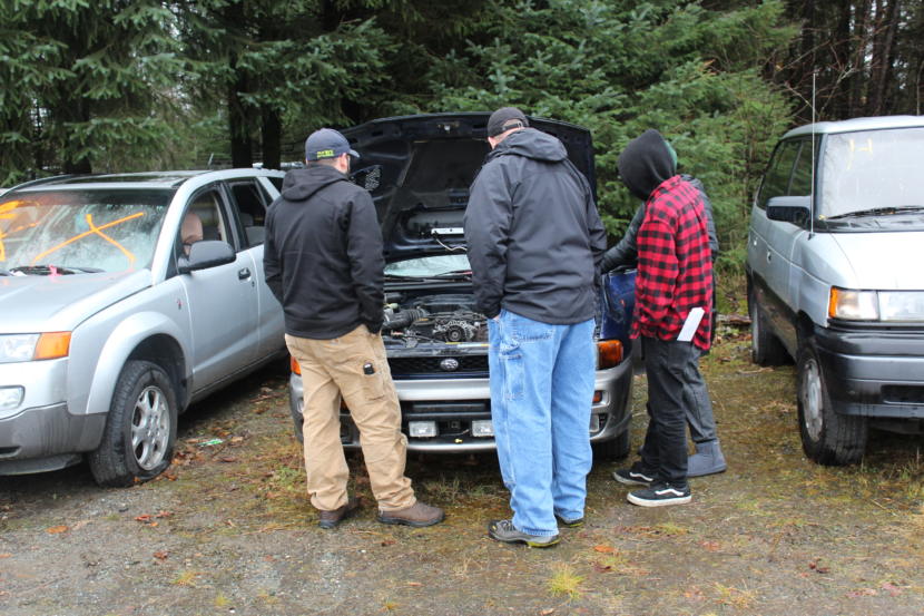 A group of prospective car buyers take a look under the hood of a Subaru at an auction at the city's impound lot in Lemon Creek, November 2018.
