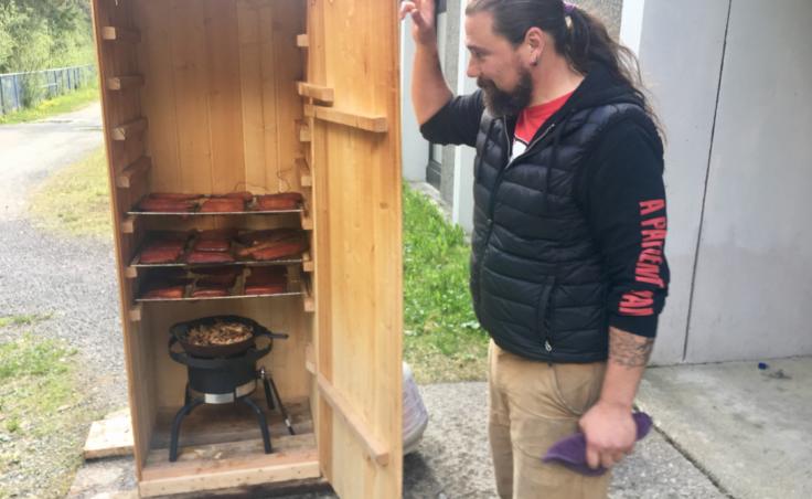 Chris Heidemann checks on the final batch of salmon on May 17, 2019. He came to school at 4:30 that morning to light the fire in the smokehouse. (Photo by Zoe Grueskin/KTOO)
