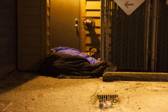 Two people and a dog curl up near a boiler room on Shattuck Way on Jan. 20, 2017 in downtown Juneau, Alaska. (Photo by Rashah McChesney/Alaska's Energy Desk)