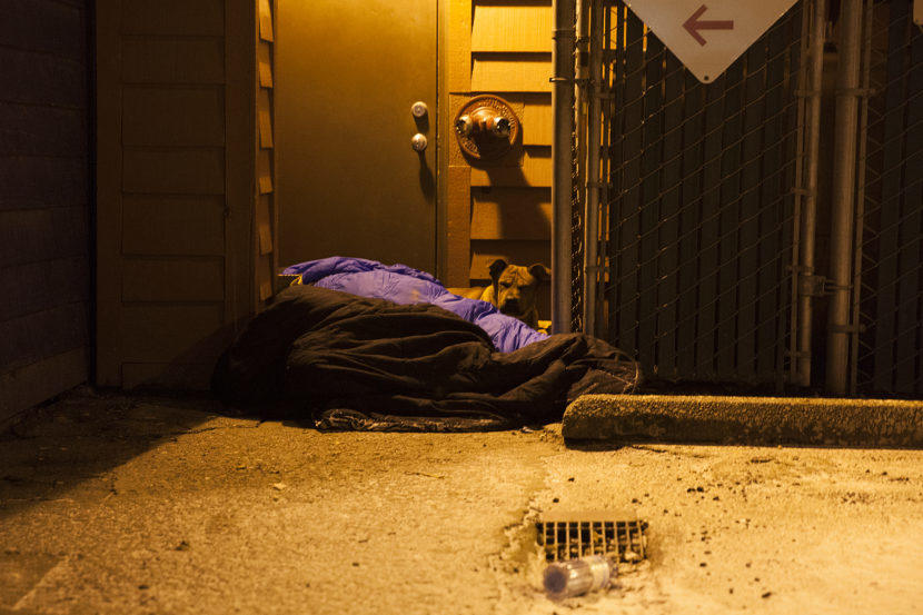 Two people and a dog curl up near a boiler room on Shattuck Way on Jan. 20, 2017 in downtown Juneau, Alaska. (Photo by Rashah McChesney/Alaska's Energy Desk)