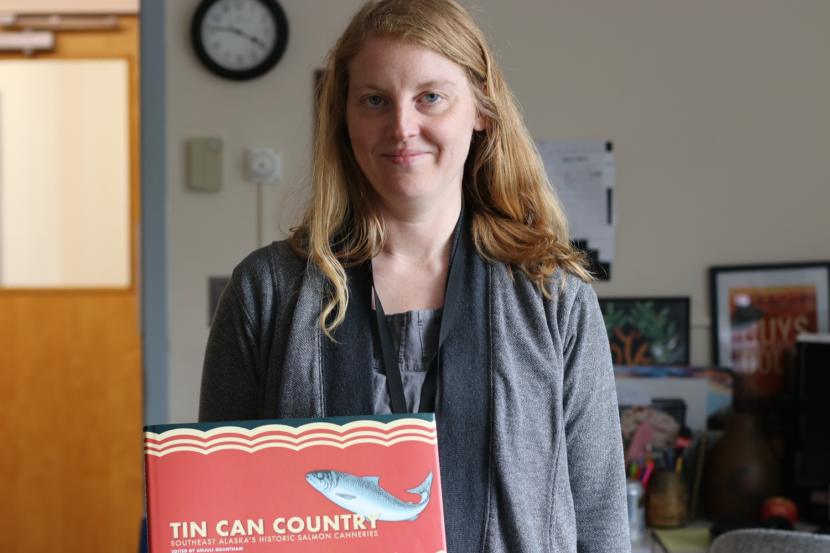 A woman holds a book in an office.