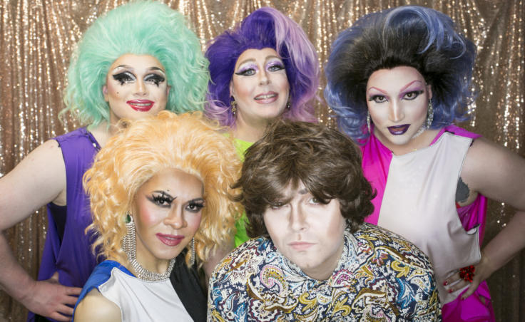 Drag performers stand in front of a gold background Juneau drag performers pose backstage at Centennial Hall for the 5th Annual GLITZ Drag Show and Juneau Pride Kickoff at Centennial Hall on Friday, June 14, 2019. Artists Lola Monèt, Shirley Wood, Miss Guise, Aura Borealis and Dear Evan Handsome took the stage for an opening number inspired by the 1969 Stonewall riots. (Photo by Annie Bartholomew/KTOO)