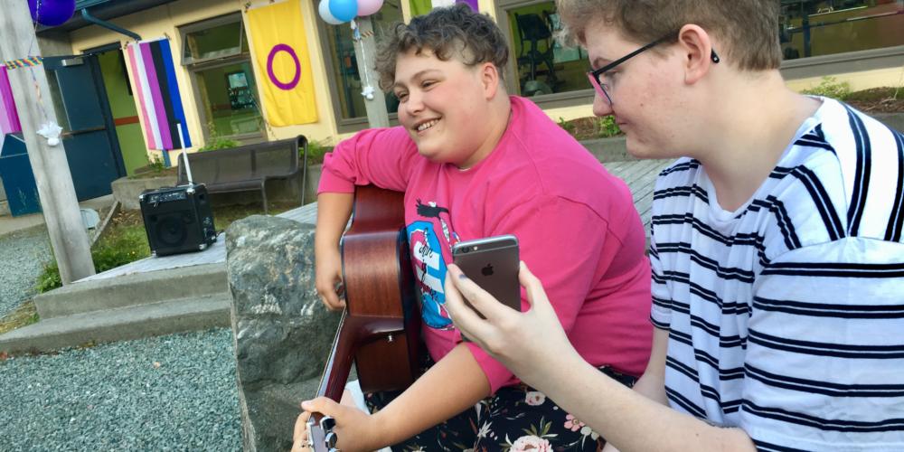 Callum Marks (right) serves as a "modern day page turner" for Theo Houck, who played a set of queer love songs at Juneau's first youth Pride party on June 20, 2019. (Photo by Zoe Grueskin/KTOO)