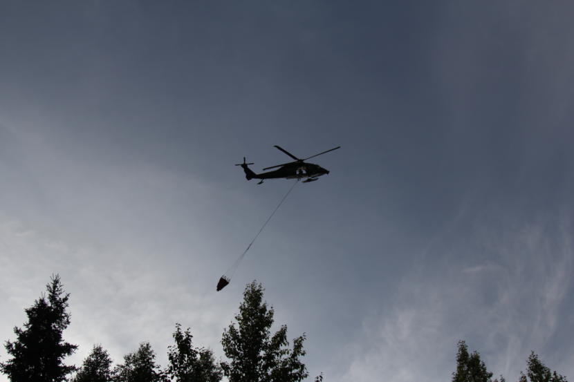 An Alaska National Guard Blackhawk helicopter circles after dropping a bucket of water on a wildfire in East Anchorage on Tuesday, July 2, 2019.