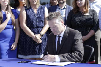 Gov. Mike Dunleavy signs Senate Bill 2002, which funds the capital budget over the next year and maintains 54 separate accounts that fund specific programs like power cost equalization, Aug. 8, 2019. (Photo by Wesley Early/Alaska Public Media)