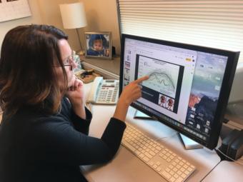 Elizabeth Siddon, photographed in her office on Aug. 1, 2019, points to a figure charting sea ice extent in the Bering Sea, which shows a "double whammy" of back-to-back low sea ice winters in 2017-18 and 2018-19. (Photo by Zoe Grueskin/KTOO)