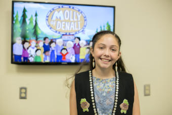 A girl in a black vest stands in front of a tv screen. Tlingit and Muckleshoot actress Sovereign Bill poses at a voice-over workshop at KTOO Public Media before the Juneau premiere of the PBS KIDS show "Molly of Denali" Saturday, August 10 at 9:30 a.m. at Elizabeth Peratrovich Hall.