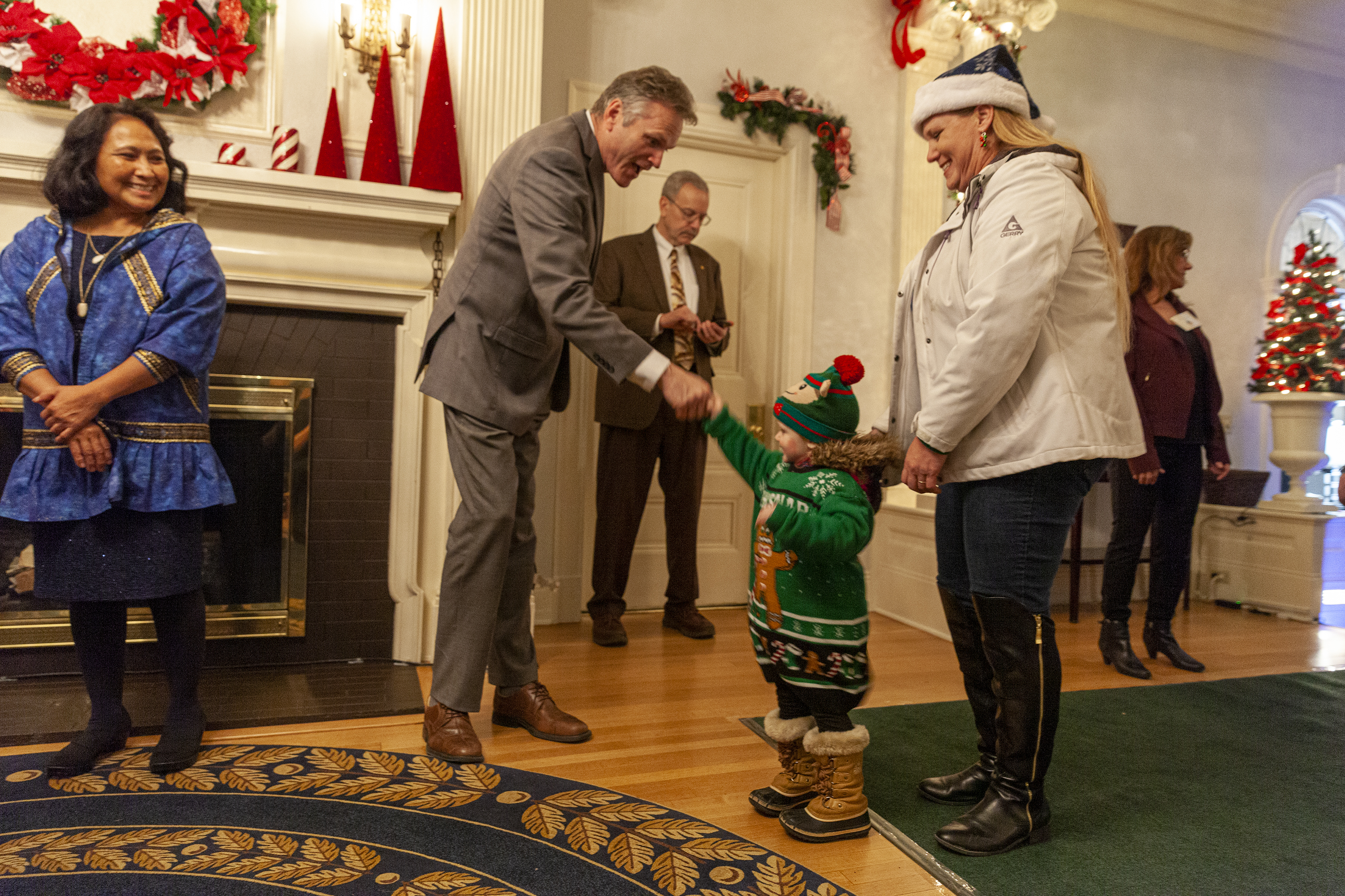 Lala Jackson, 2, shakes Gov. Mike Dunleavy's hand during the annual Christmas open house on Tuesday, Dec. 10, 2019, in Juneau, Alaska. According to the Governor's office, 15,000 cookies were baked and more than 100 pounds of fudge and chocolate candy was on hand for visitors.