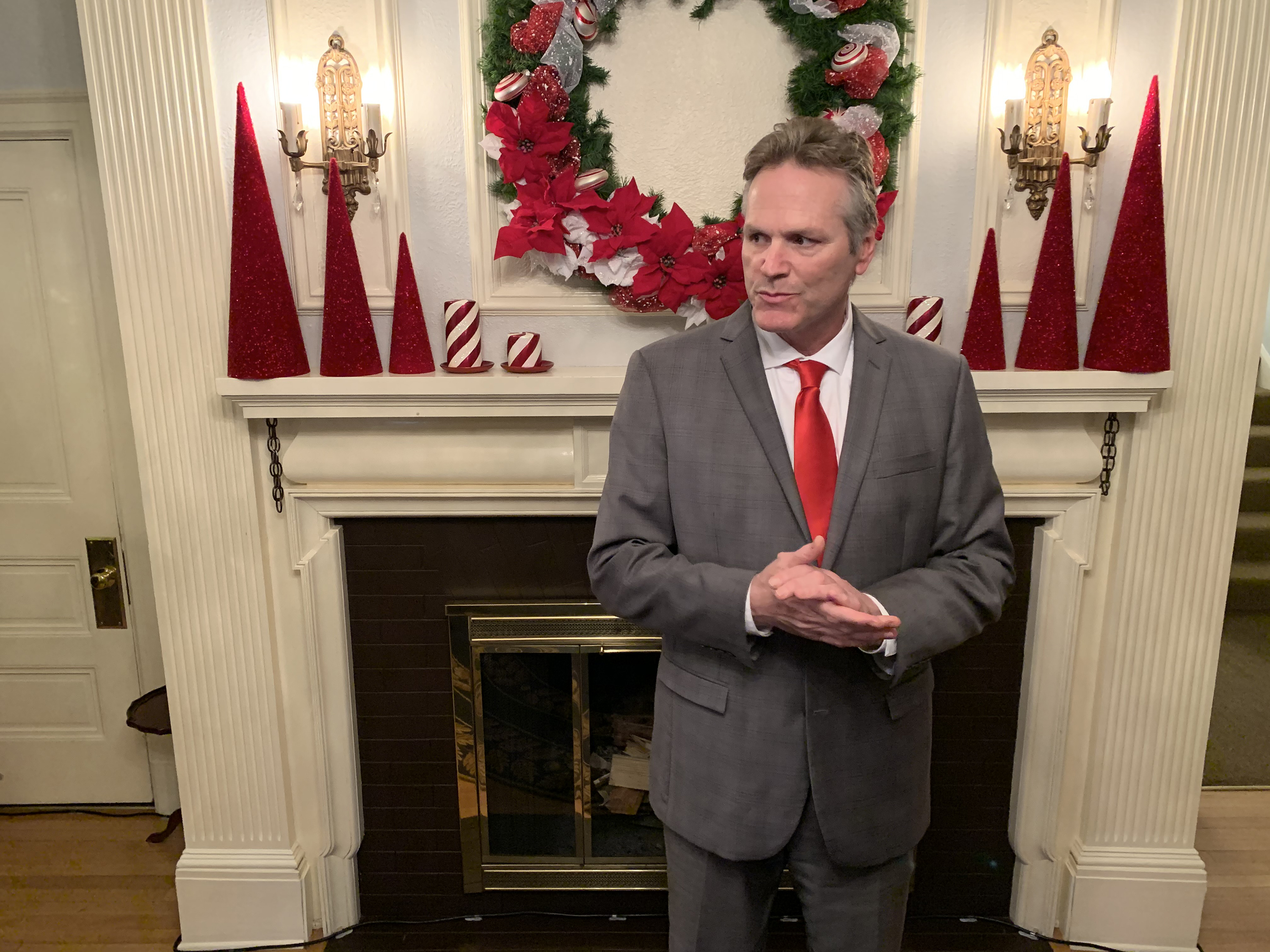 Gov. Mike Dunleavy waits for guests at the annual Christmas open house on Tuesday, Dec. 10, 2019 in Juneau, Alaska.