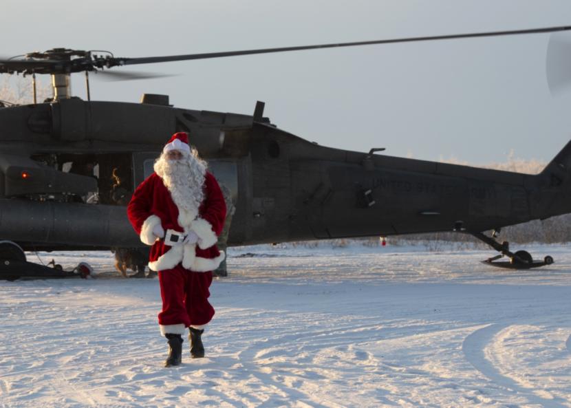 A man dressed as Santa Claus walks out of a Black Hawk helicopter.
