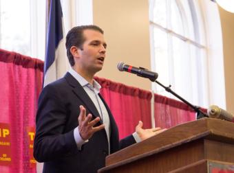 Donald Trump Jr. speaks into a microphone at a podium.