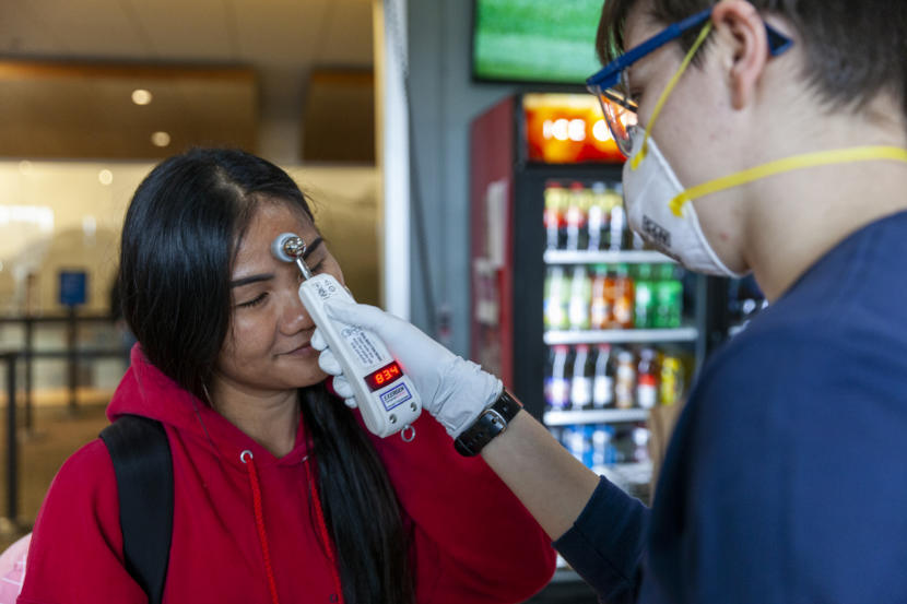 Namfon Noisai gets her tempoerature checked by Capital City Fire and Rescue's Lily Kincaid during a voluntary screening at the Juneau International Airport on Saturday, March 21, 2020 in Juneau, Alaska. Lily Kincaid asks Richard Clarke questions about where he traveled and who he was with before taking his temperature on Saturday, March 21, 2020 in Juneau, Alaska. The airport sees multiple daily flights to and from Seattle — one of the epicenters of coronavirus spread in the United States. Passengers arriving at the airport can request to have their temperature checked. Anyone with a temperature above 100.4 degrees will be advised to contact medical providers and to self-quarantine. (Photo by Rashah McChesney/KTOO)