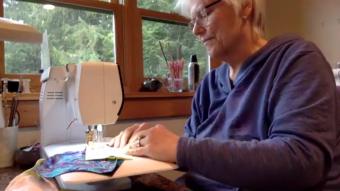 Candy Behrends sews together a chain of mask liners and patterns together from her home in Juneau in this still frame from a video call on April 22, 2020.