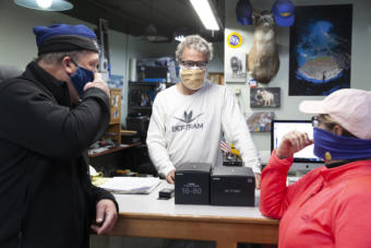 Dave Harris, Art Sutch and Isabel Lee talk about a camera package during one of Sutch’s last days operating a brick and mortar camera shop on Saturday, April 25, 2020, in Juneau, Alaska. (Photo by Rashah McChesney/KTOO)