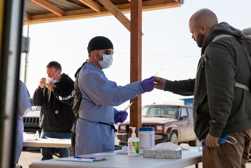 Volunteer Lucas Salzbrun hands out swabs and gives directions on how to do a self-swab at the airport coronavirus test site in Bethel, Alaska on April 29, 2020. (Photo courtesy Katie Basile/KYUK)