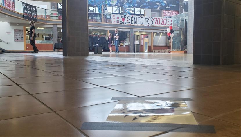 Staff and a photographer in the lobby of Juneau-Douglas High School: Yadaa.at Kale stand by for the next senior and their short list of guests to walk the graduation stage on May 18, 2020.