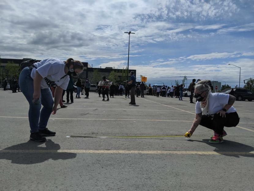Organizers of the “I Can’t Breathe” rally in Anchorage place duct tape lines 6 feet apart to guide people where to stand during the rally on Saturday. (Photo by Mayowa Aina/Alaska Public Media)