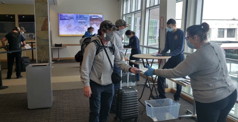 A passenger off of a flight from Seattle hands paperwork to a screener related to a COVID-19 health mandate at Juneau International Airport on June 26, 2020.