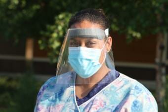 A nursing assistant wearing a mask and face shield outside the Providence Transitional Care Center in Anchorage.